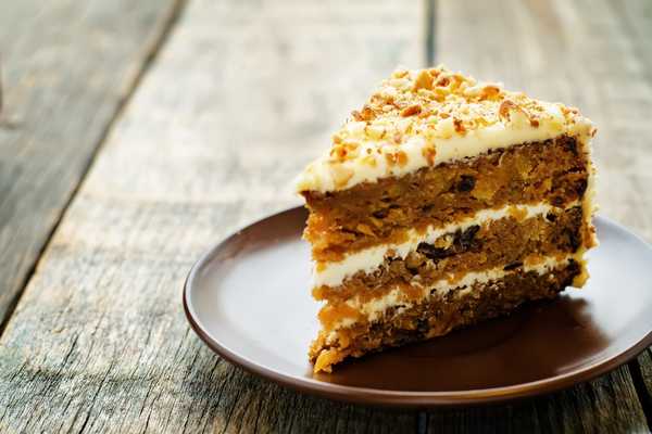 Carrot Cake Day. Photo of three layered carrot cake with white icing on a plate.