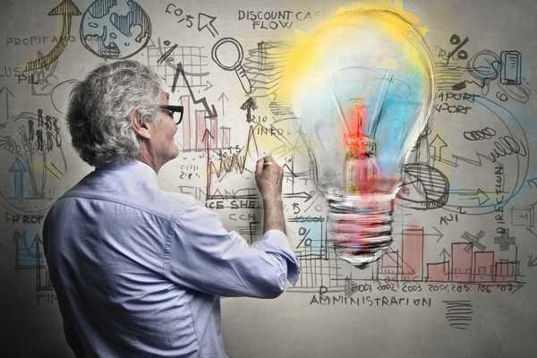 Inventors Day. May who looks like a scientist drawing mindmaps on a wall