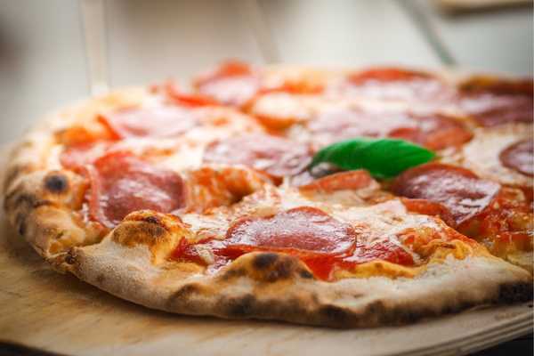 National Pizza Day. Pepperoni pizza sitting on a wooden board