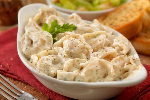 National Tortellini Day. Bowl of tortellini pasta in creamy white sauce