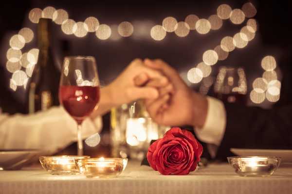 Valentine’s Day. Two people having a romantic dinner holding hands.