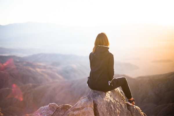 World Thinking Day. Lady sitting at the top of a mountain looking at the view