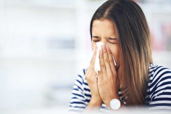 Lady sneezing into a tissue for Allergy Awareness Week