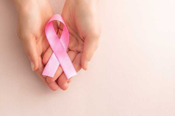 Pink ribbon in a hand for Cancer Survivors Day