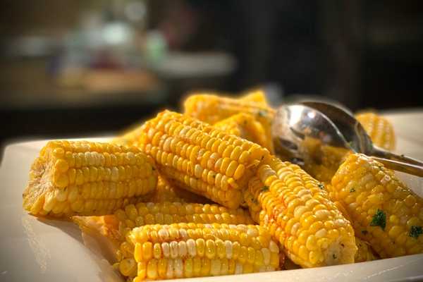 Cooked corn on the cobs piled up on a plate for Corn on the Cob Day