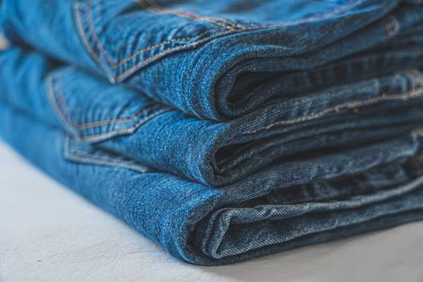 Three pairs of jeans folded and stacked on top of each other for Denim Day