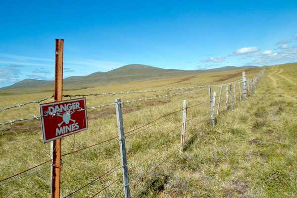 Sign that says danger mines in front of hills for International Day of Mine Awareness