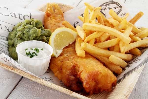 Batter fish and chips on a plate with tartar sauce and mushy peas for National Fish and Chip Day