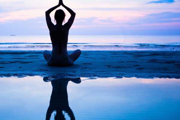 Person in yoga position on a beach for World Health Day