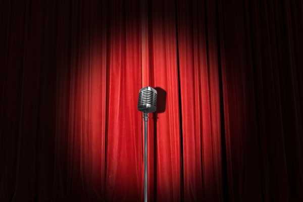 Empty stage with red curtains pulled and microphone for Glasgow International Comedy Festival
