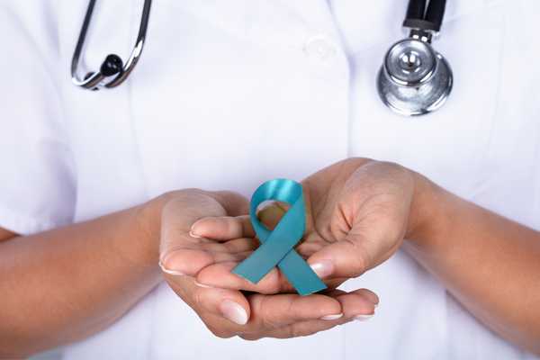 Female doctor holding a blue ribbon for Ovarian Cancer Awareness Month