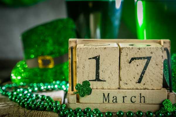 The number 17 and March on blocks surrounded by shamrocks and a green leprechaun hat for St Patrick's Day