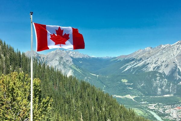 Canadian flag flying with mountains in the background for Canada Day
