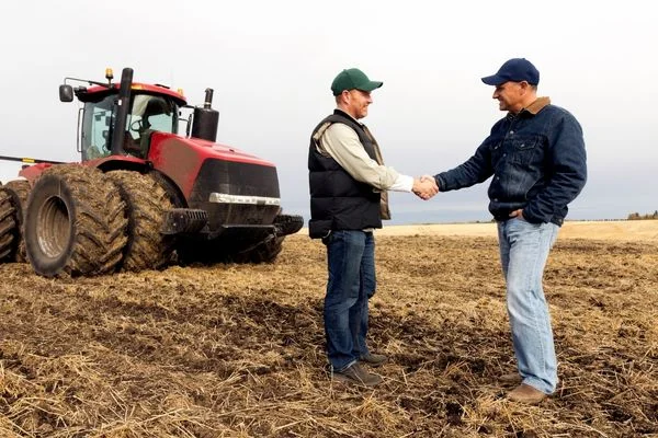 Farmers shaking hands in a field for International Day of Cooperatives