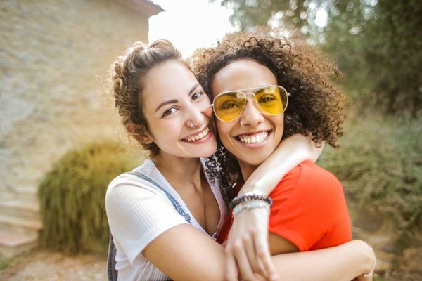 Two female friends hugging each other and smiling for International Day of Friendship