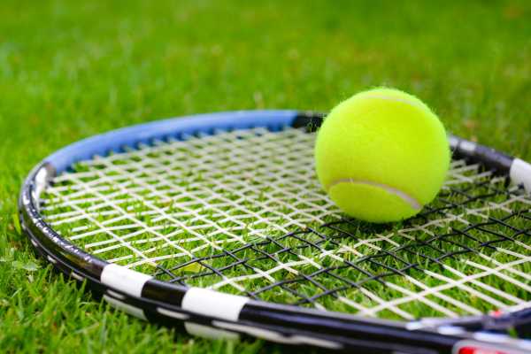 Tennis racket with a tennis ball lying on a tennis court for the French Open tennis tournament