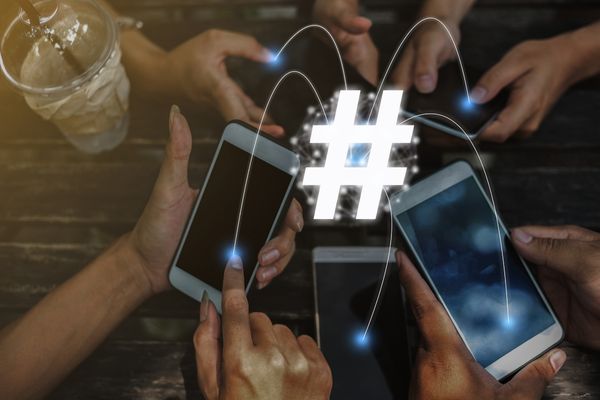 Hashtag symbol overlaid on a photo of people on their phones for Hashtag Day