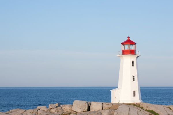 White lighthouse with red top overlooking the sea for National Lighthouse Day