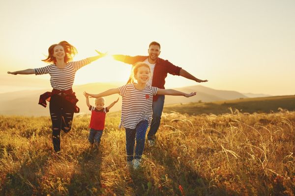 Family running in the countryside with arms out like an aeroplane for National Son's and Daughter's Day