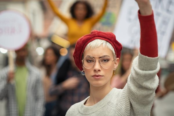 Woman with hand in the air at a demonstration for Women's Equality Day