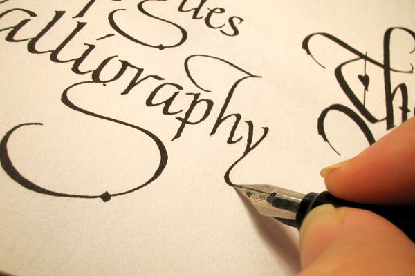 Person writing the word calligraphy with a fountain pen for World Calligraphy Day