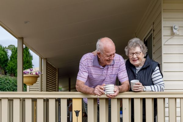 Two elderly people with cups of coffee learning on a balcony for World Senior Citizens Day