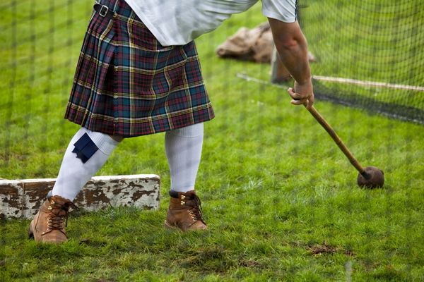 Person wearing a kilt and holding a croquet mallet for Braemar Gathering (Highland Games)