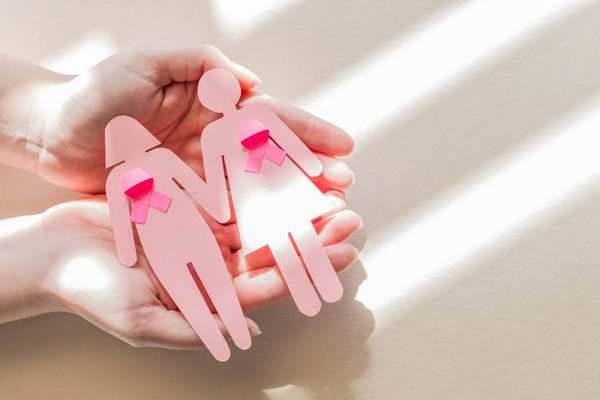 Two pink paper dolls wearing pink ribbons for Breast Cancer Awareness Month