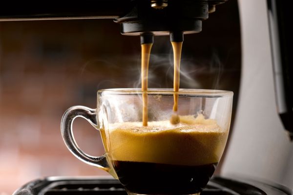 Espresso coffee being poured into a glass cup for Espresso Day