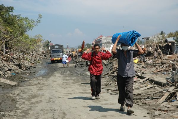 People carrying items on their heads down a road for International Day for the Eradication of Poverty