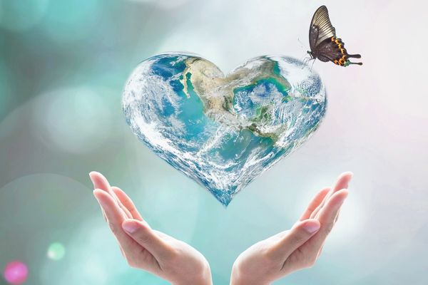 Two hands holding a heart with the earth printed inside and a butterfly resting on it for International Day for the Preservation of the Ozone Layer