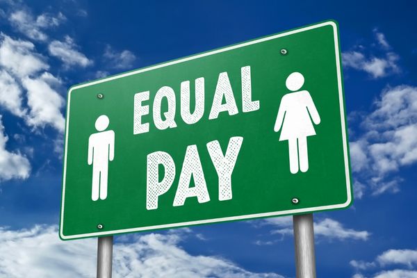 Green sign with white text reading "Equal Pay" with a male and female symbol for International Equal Pay Day