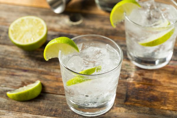 Glass of gin and tonic with lime on a wooden table for International Gin and Tonic Day