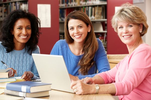 3 women of different ages gathered around a laptop for Lifelong Learning Week