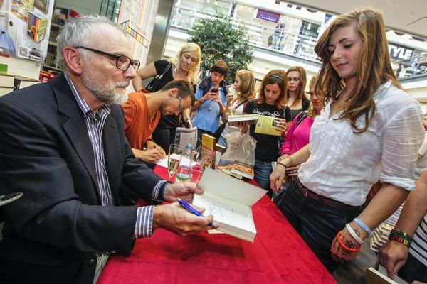 Author signing a book for a crowd of people for National Authors Day