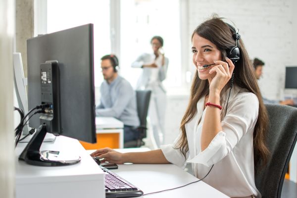 Woman looking at a computer screen and speaking into a headset for National Customer Service Week