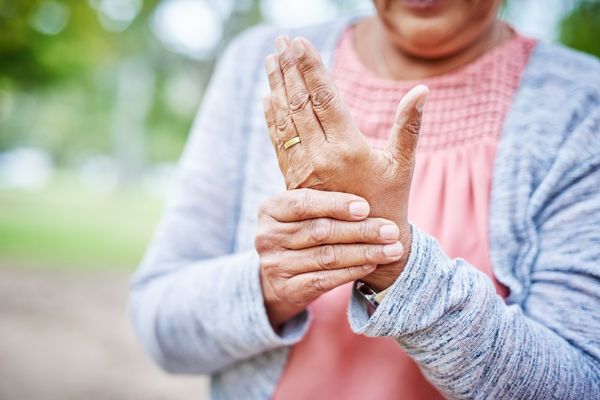 Elderly lady holding her own hand by the wrist for World Arthritis Day