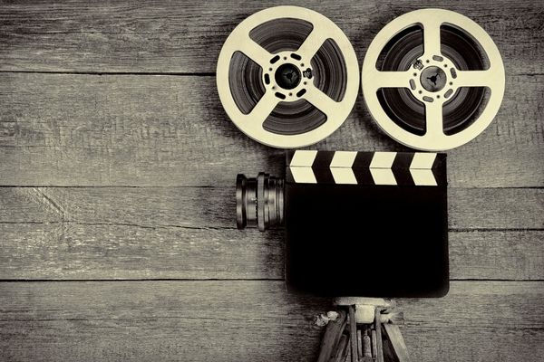 Wooden background with a clapperboard and film reels for World Day for Audio Visual Heritage