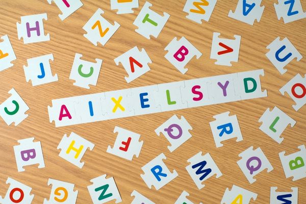 Wooden table with cut out paper letters and the world "dyslexia" spelled "aixelsyd" for World Dyslexia Awareness Week