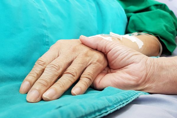 Hand holding the hand of an elderly person which has a cannula in for World Hospice Palliative Care Day