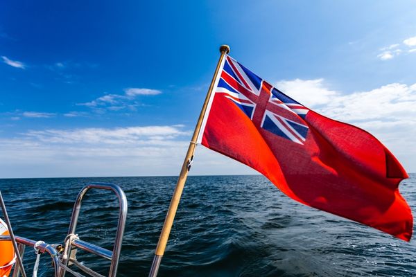 Red flag with Union Jack in the left corner waving at sea for World Maritime Day