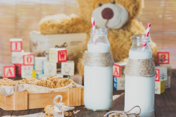Bottles of Milk on a table with a teddy bear behind them for World School Milk Day