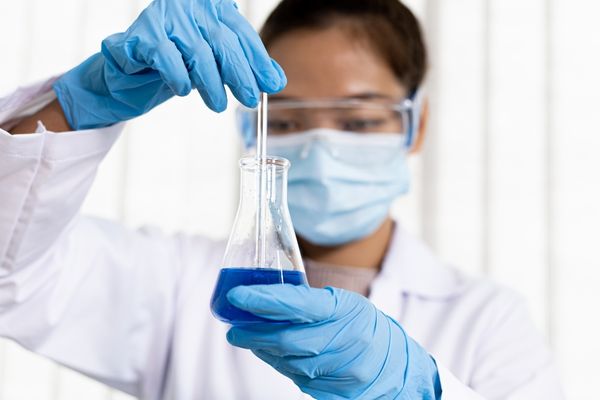 Scientist holding a vial of blue liquid for World Science Day for Peace and Development