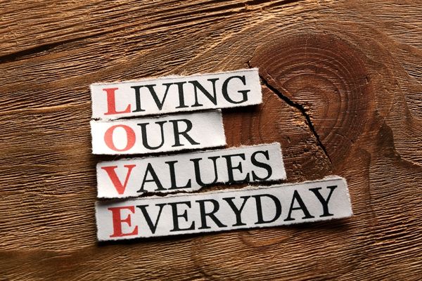 Strips of paper reading "Living our values every day" against a wooden background for World Values Day