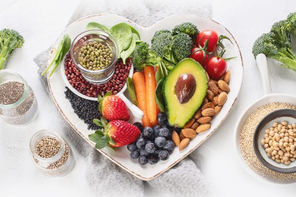 Array of fruit, vegetables and nuts on a white heart-shaped plate for World Vegan Month