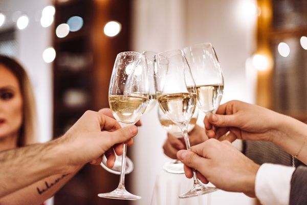 Three people clinking glasses for National Champagne Day
