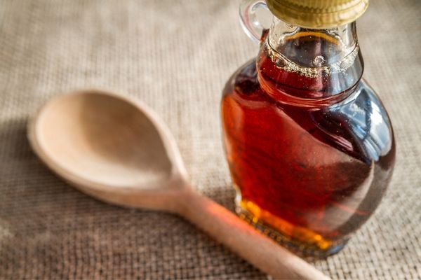 Bottle of maple syrup and a wooden spoon for National Maple Syrup Day