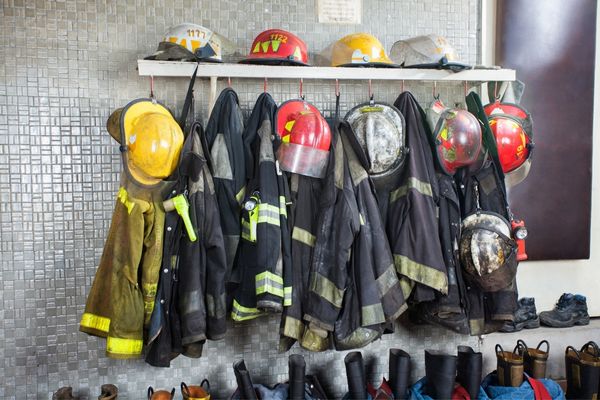 Fire service uniforms and helmets hanging on a rack for National Workplace Day of Remembrance