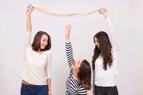 Two girls holding up a piece of cloth, one girl reaching up but unable to reach for Short Girl Appreciation Day
