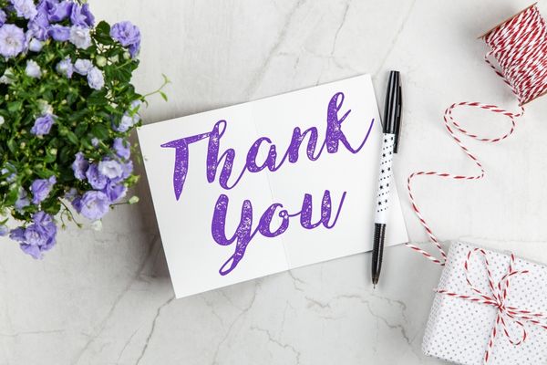 Thank you card with purple flowers beside it for National Thank you Notes Day
